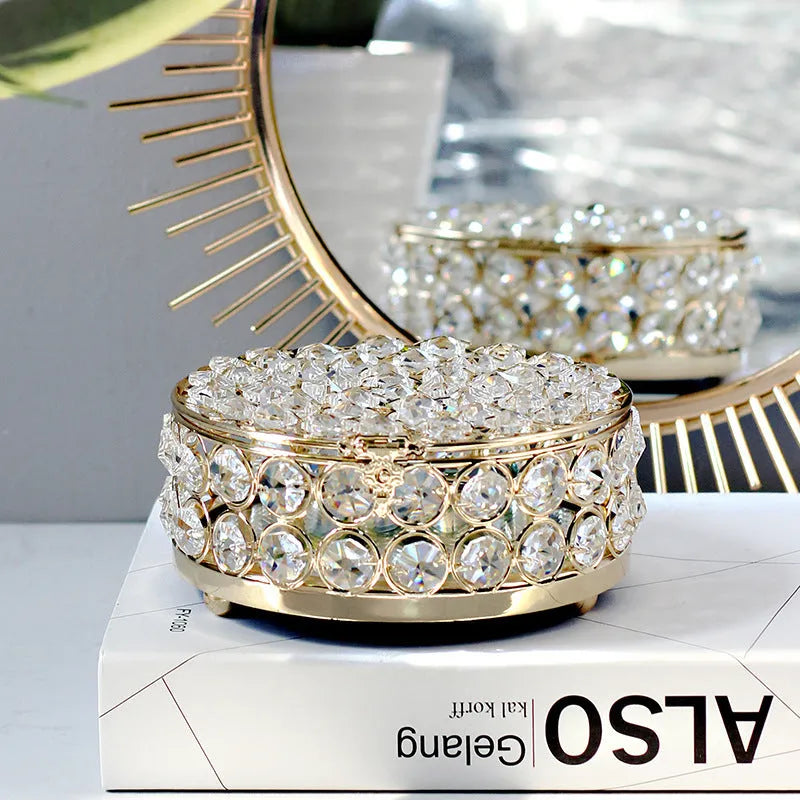 Transparent crystal glass jewelry box with a French gold metal frame on a table.