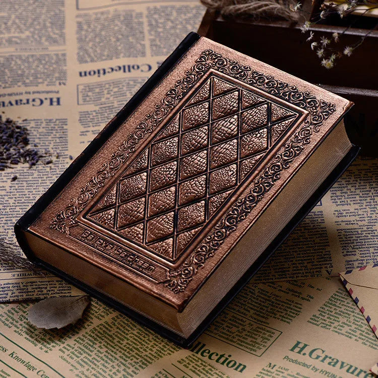 A5 hardback notebook with embossed faux leather cover in bronze colour, shown open on a table.
