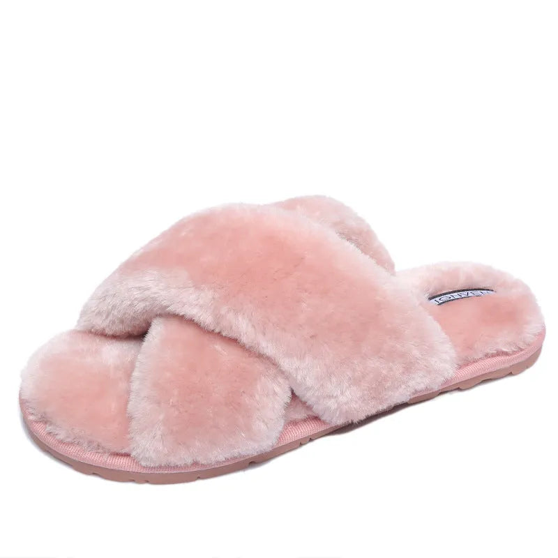 Women's black cross-strap open-toe fur slippers showing the patterned non-slip rubber sole.