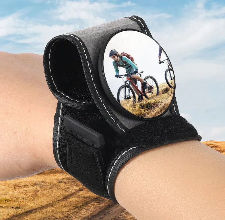 Black nylon wrist-mounted bicycle rear-view mirror with velcro strap and armoured glass reflective surface.