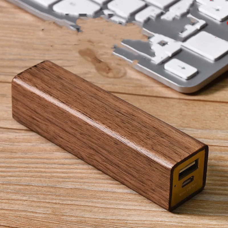 Brown walnut wood portable power bank with USB port next to its gift box.