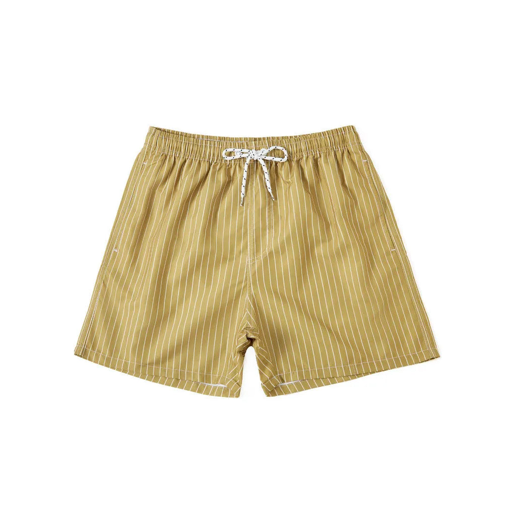 Man wearing grey striped polyester beach shorts with a straight leg opening, on a beach.