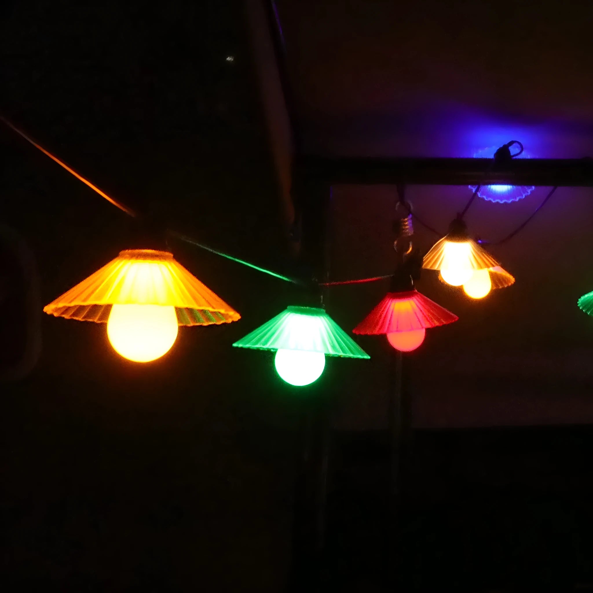 Outdoor LED string lights with flower-shaped bulbs hanging in a garden setting.