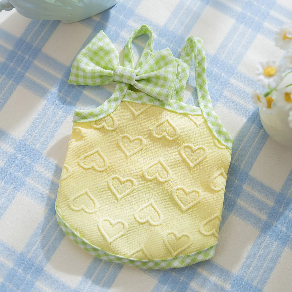 Small dog wearing blue elastic vest with heart pattern and bow suspenders
