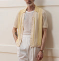 A bright yellow men's short-sleeved polo shirt with hollow-out asymmetric patterning on a casual model.