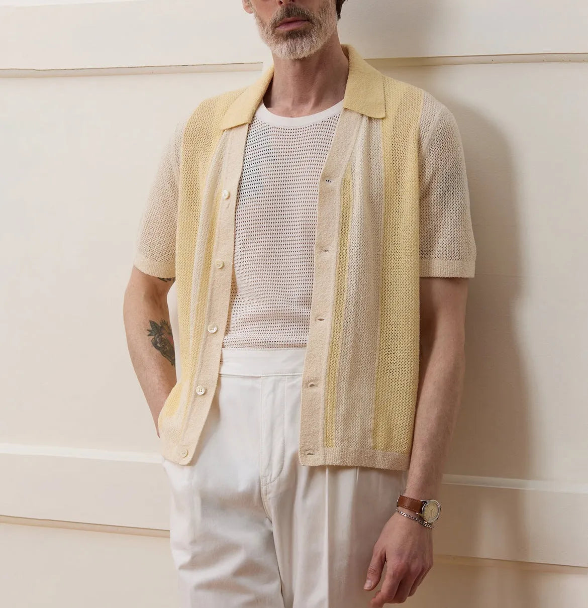 A bright yellow men's short-sleeved polo shirt with hollow-out asymmetric patterning on a casual model.
