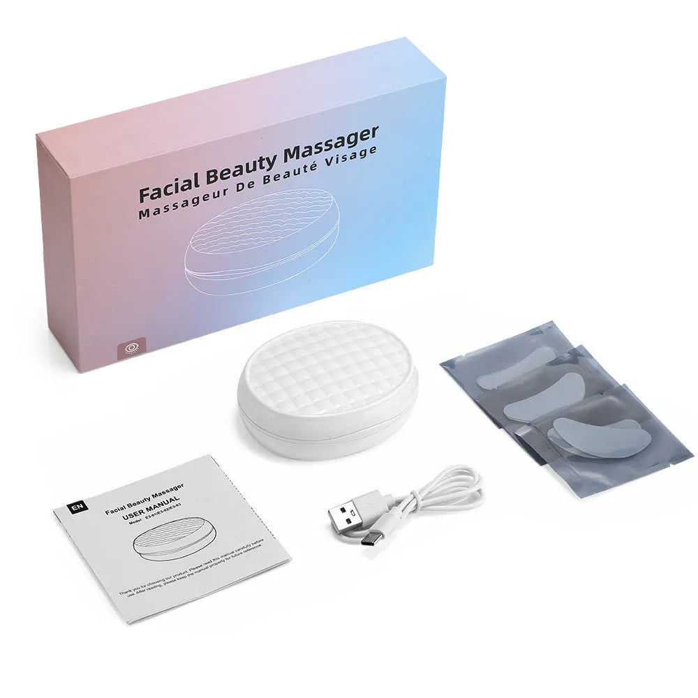 White wireless red light EMS eye and face two-in-one massage device on a table.