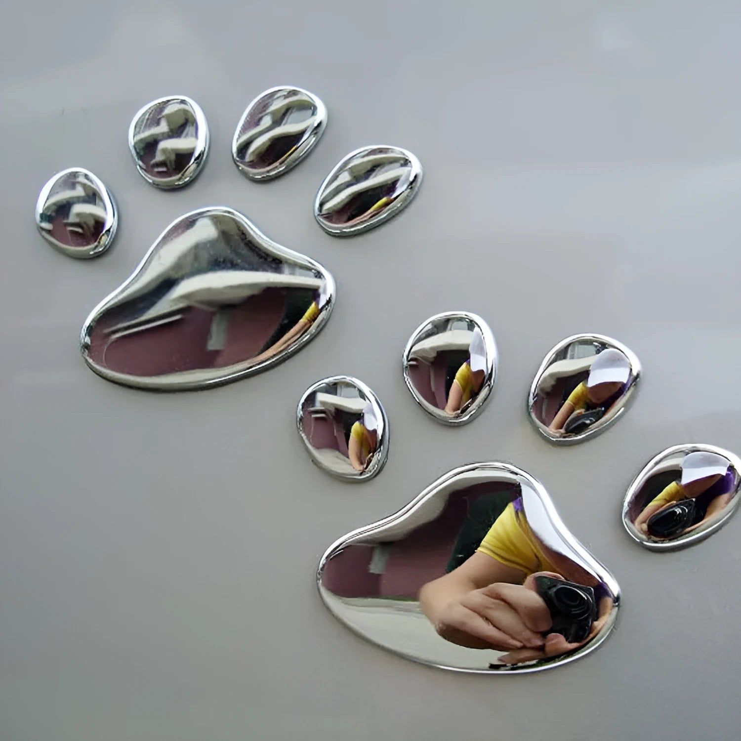 Pair of hand-shaped brush stroke car stickers with dog footprint details on a vehicle bumper.