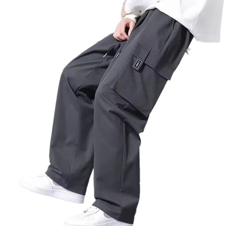 Boy wearing grey straight leg cargo pants with drawstring waist and large side pockets.