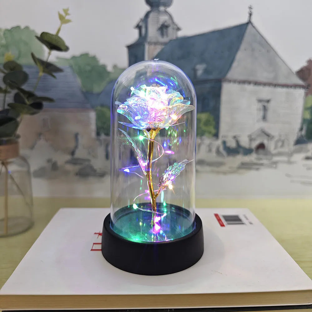 Small glass night lamp with plastic flowers on a black base.