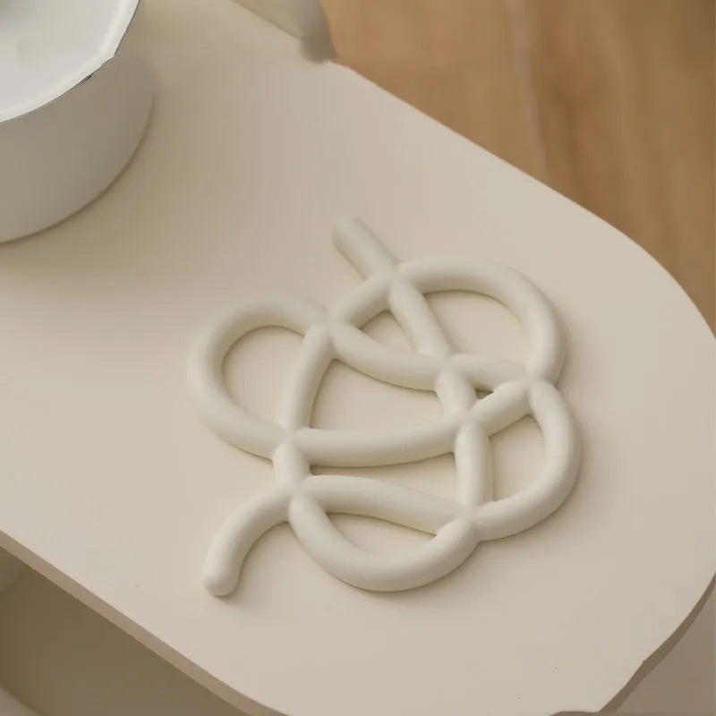 Ceramic heat proof mat in an irregular shape on a kitchen countertop.