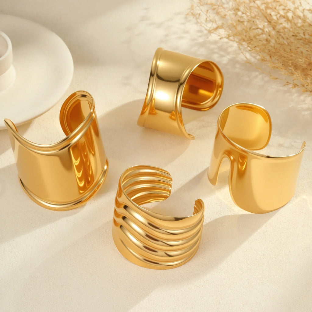 Women's stainless steel bracelet with 18K gold plating featuring geometric wave design and exaggerated wide band
