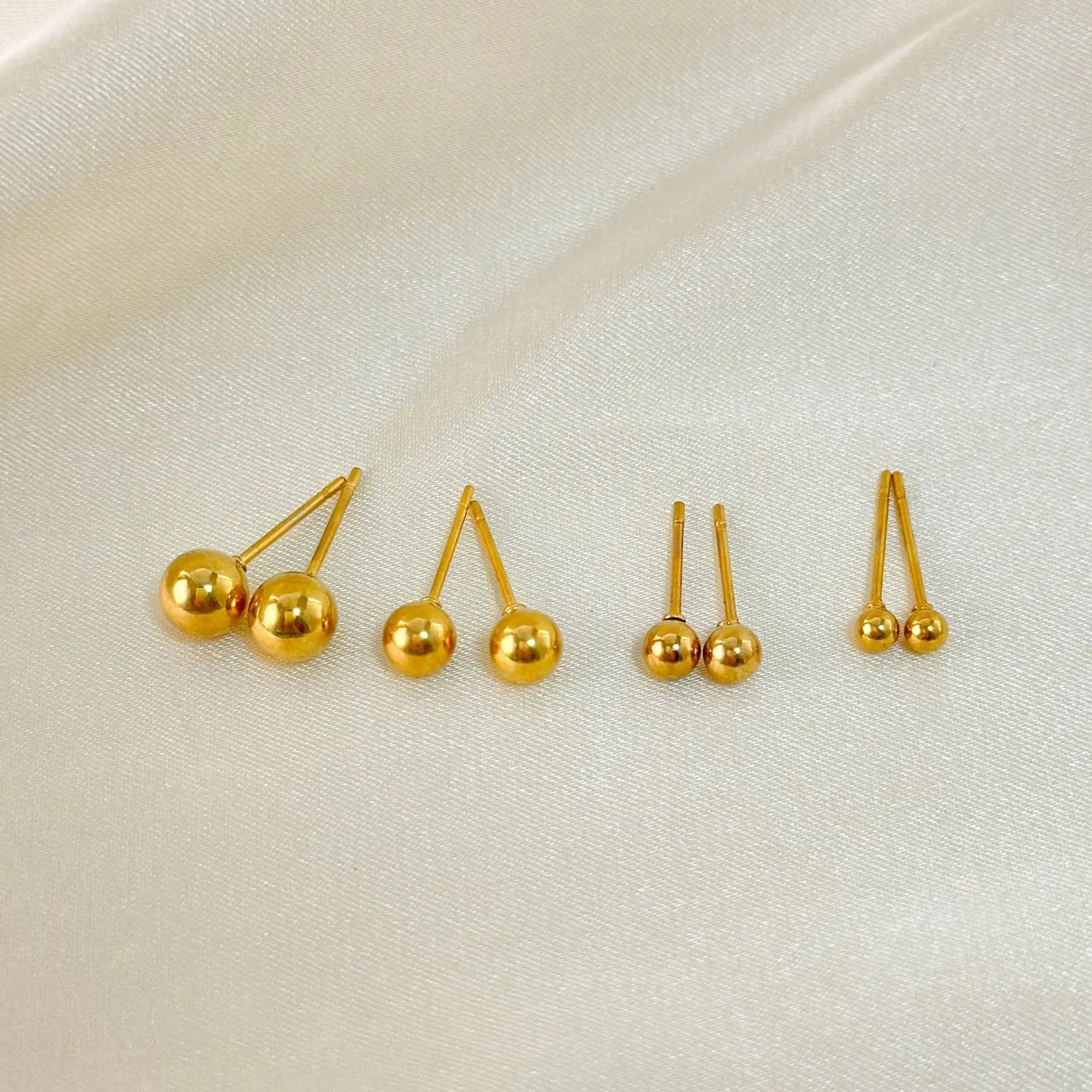 Stainless steel 18K gold ball stud earrings in round geometric design on simple stud posts.