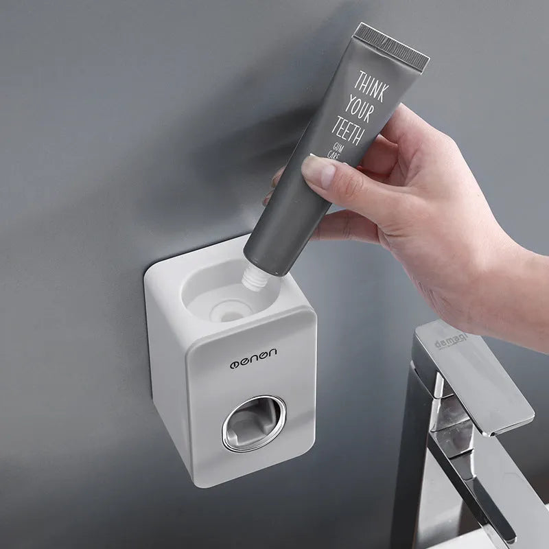 White and grey wall mounted automatic toothpaste dispenser with toothbrush rack, shown in grey, green and pink colour options.
