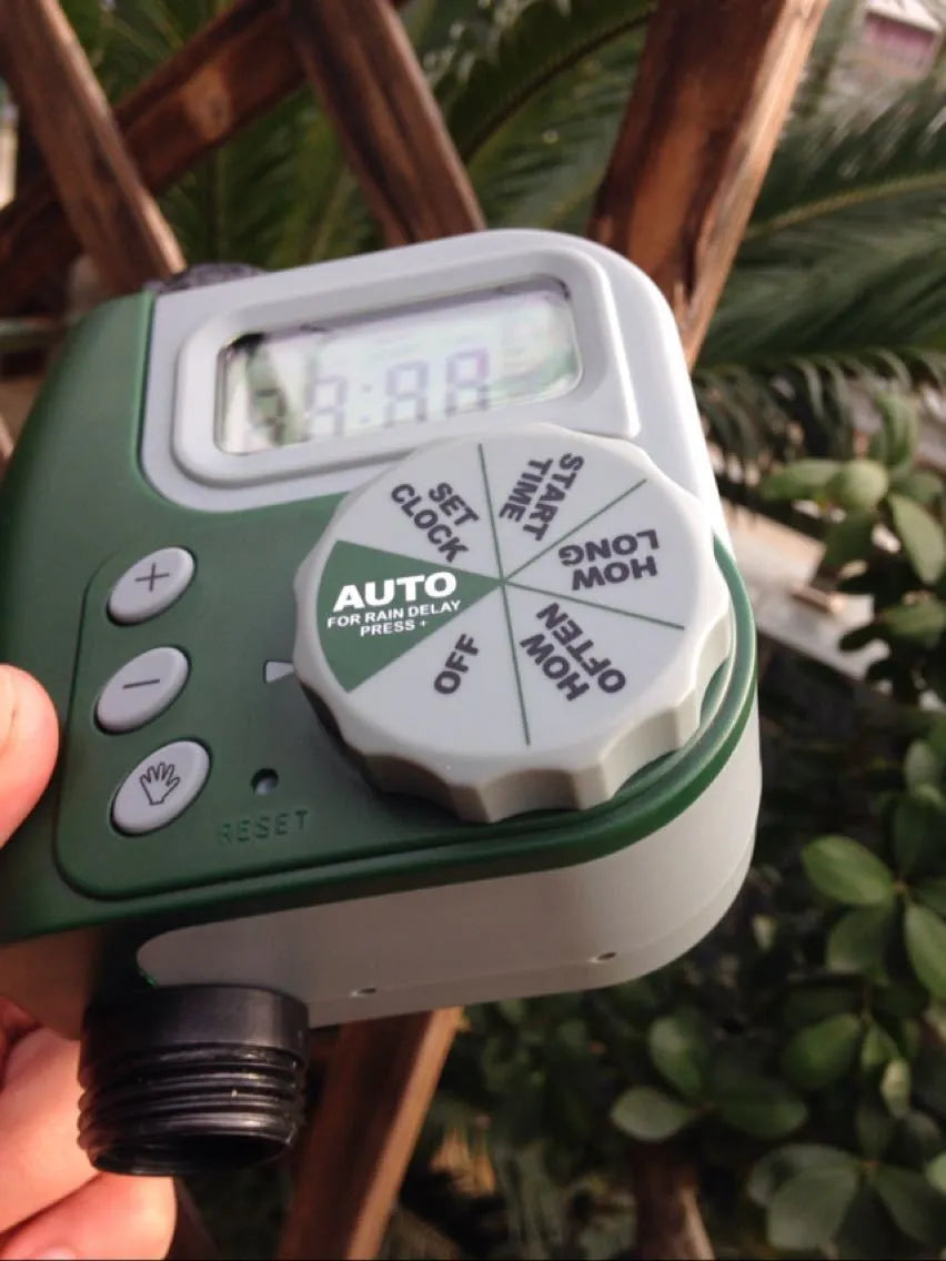Green digital programmable water timer for garden hose with copper connector and LCD screen.