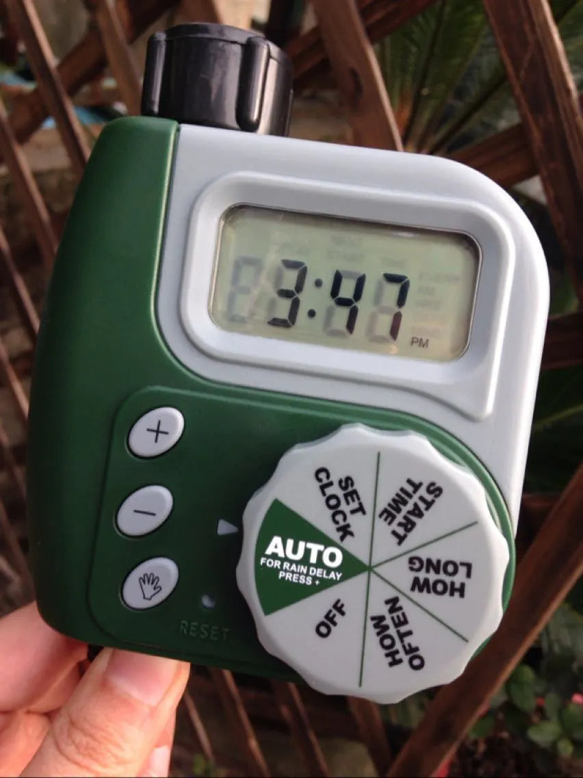 Green digital programmable water timer for garden hose with copper connector and LCD screen.