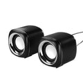 Pair of mini desktop speakers with 3.5mm audio plug on desk beside laptop