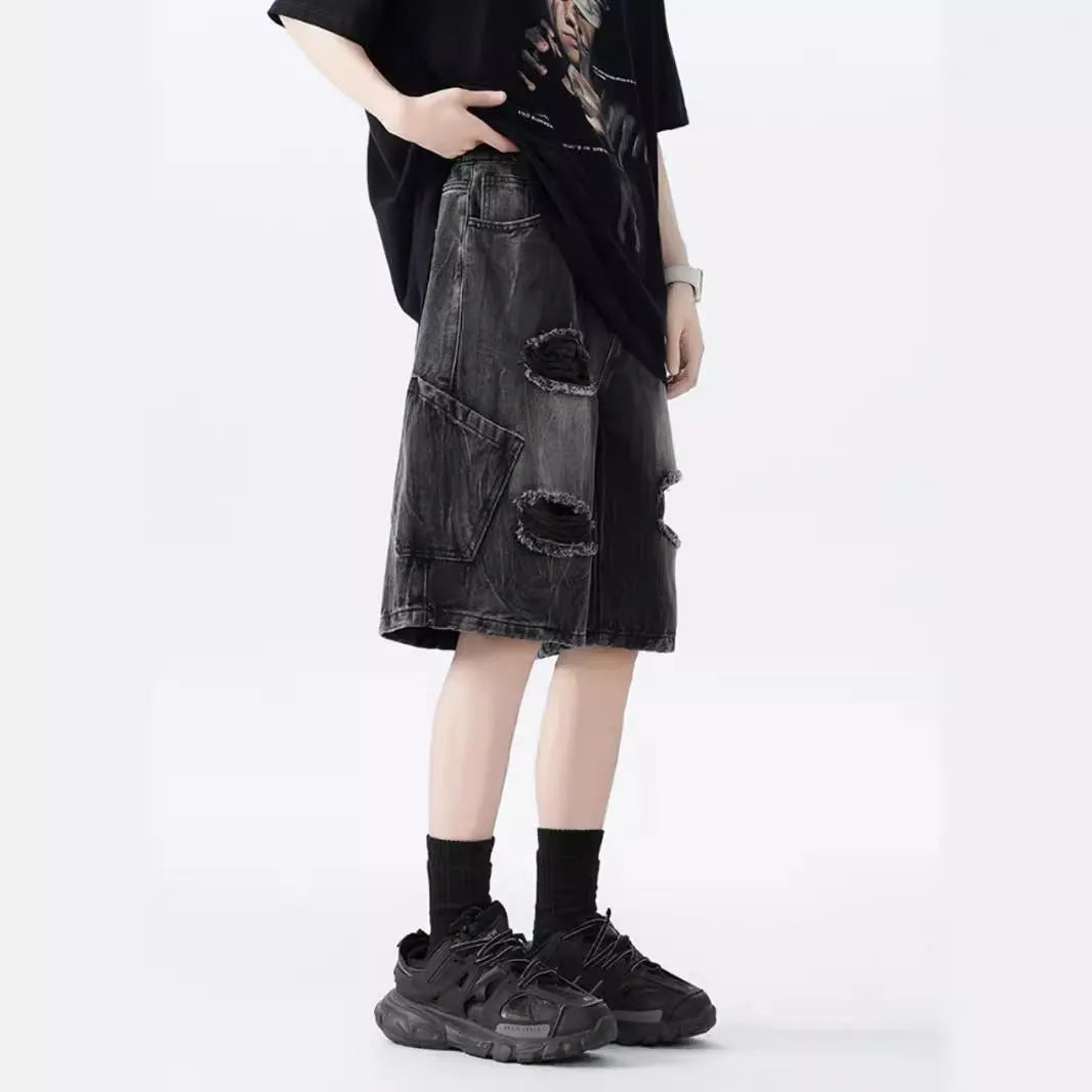 Man wearing black washed ripped denim shorts in a loose, retro style