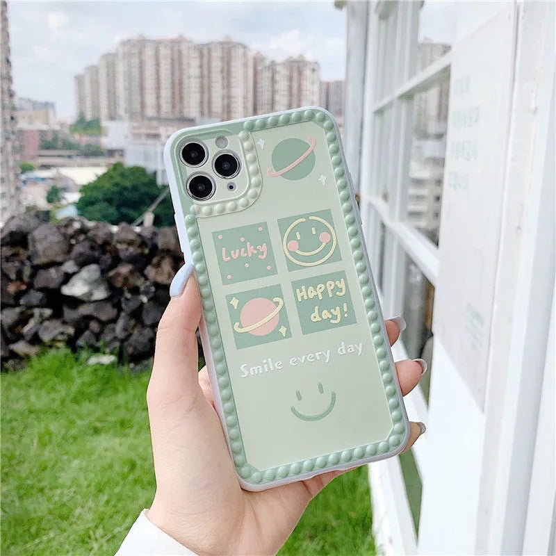 Green iPhone case with geometric smiley face design and polka dot frame on a TPU back cover.