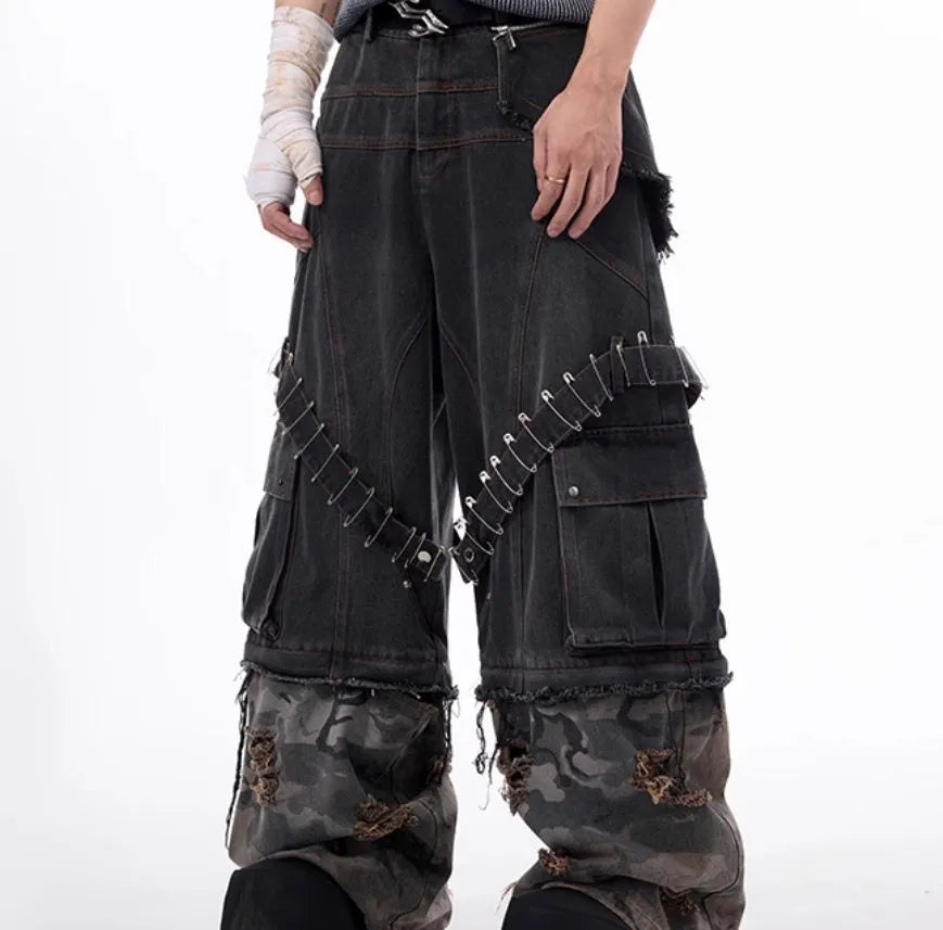 Men's grey cotton jeans with camouflage print, splicing panels, and decorative pin and ribbon details.