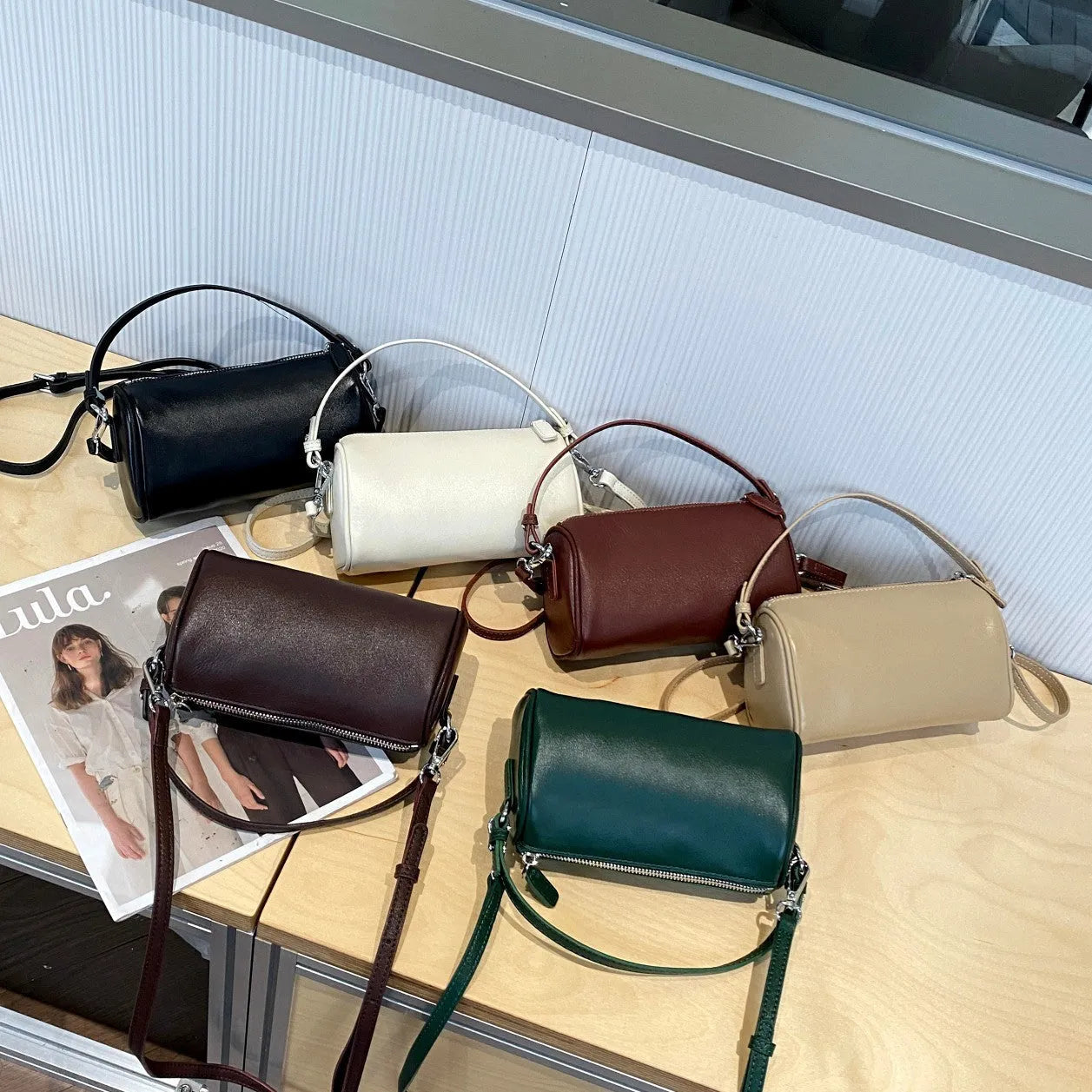 Men's cylindrical leather crossbody phone bag in black, shown with visible stitching and shoulder strap