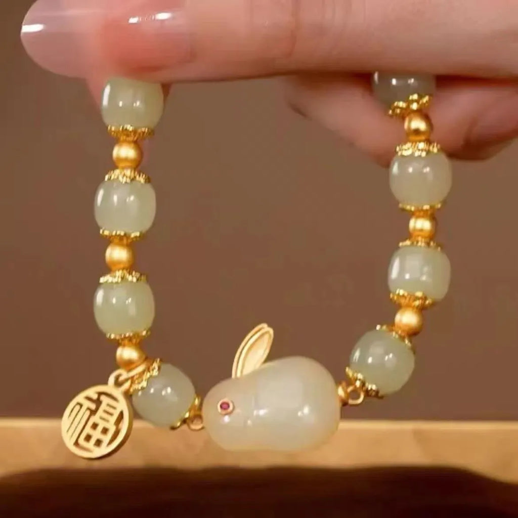 Women's black bracelet with a green jade hare charm, fu character symbol and lily motif design.