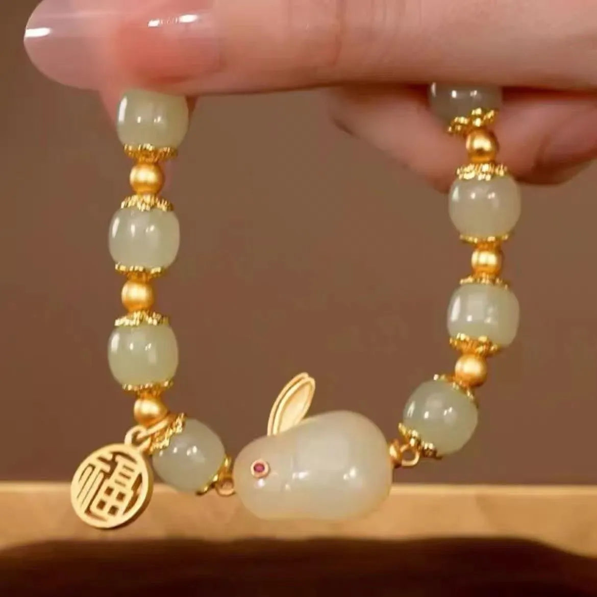 Women's black bracelet with a green jade hare charm, fu character symbol and lily motif design.