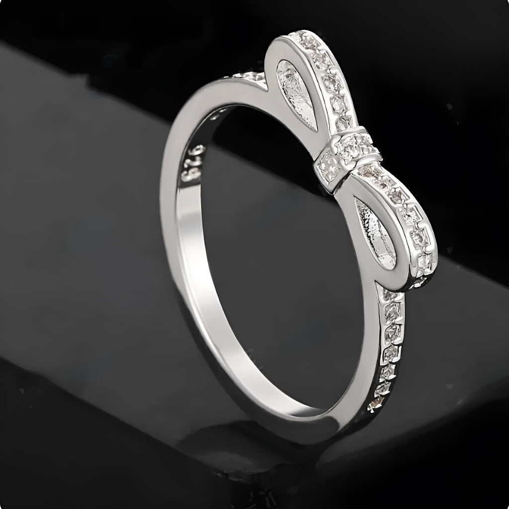 Silver plated bow-shaped ring with clear rhinestone crystal decoration on a model finger