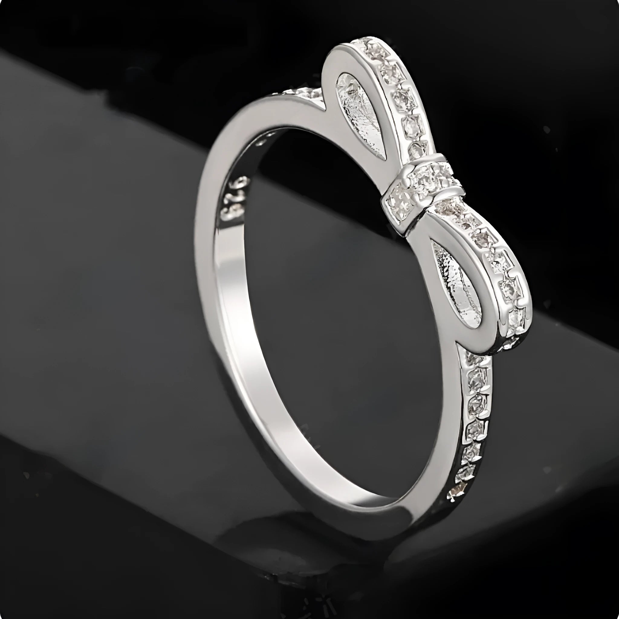 Silver plated bow-shaped ring with clear rhinestone crystal decoration on a model finger