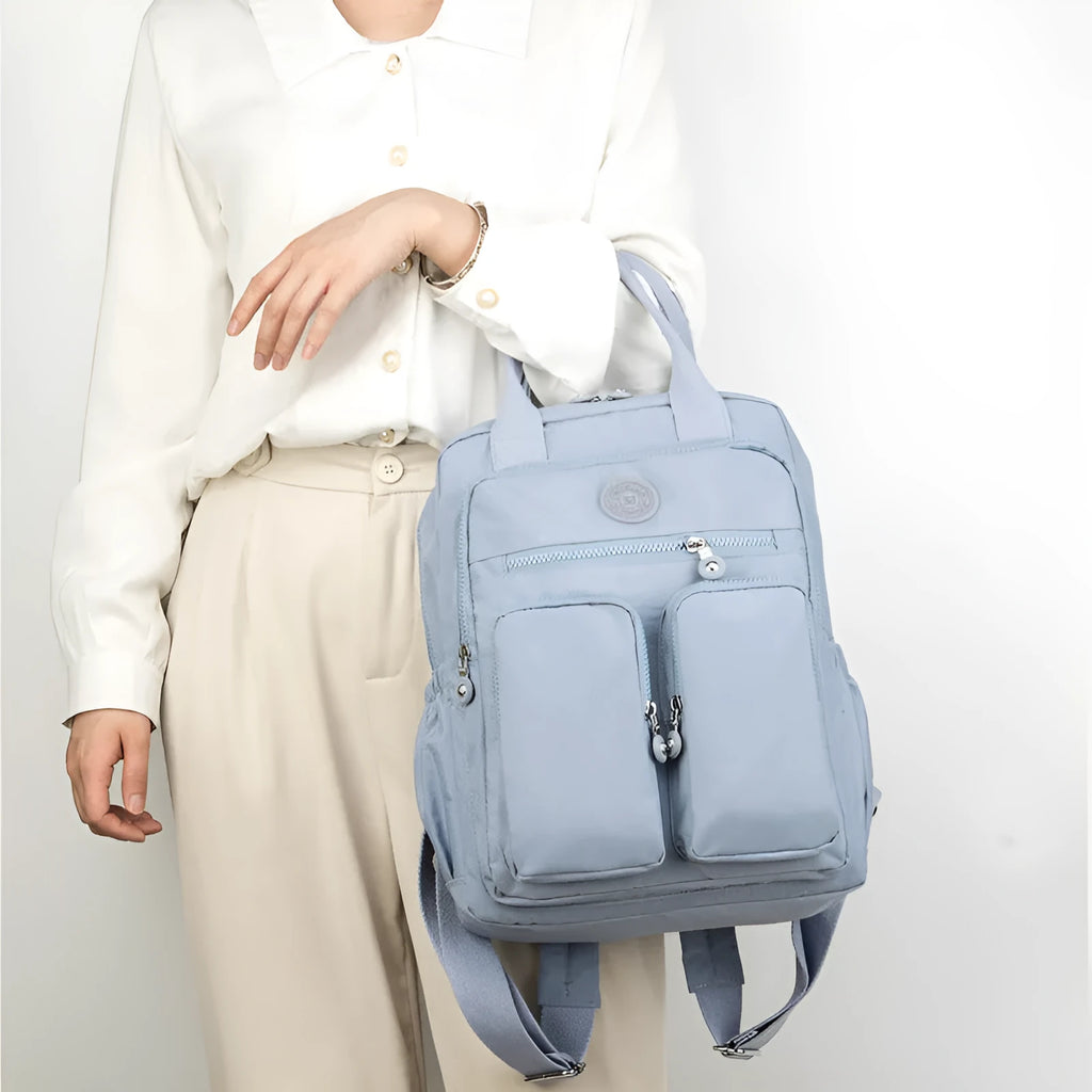 Waterproof nylon women's backpack in grey showing front pockets and internal laptop compartment.