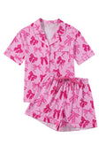 Women's pink polyester pajama set with bow print, featuring a top and trousers.