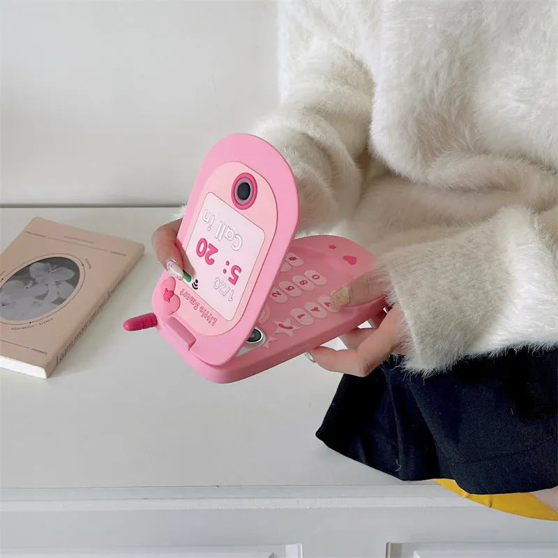 Light pink silicone flip phone case with a built-in mirror, open and showing iPhone model compatibility.