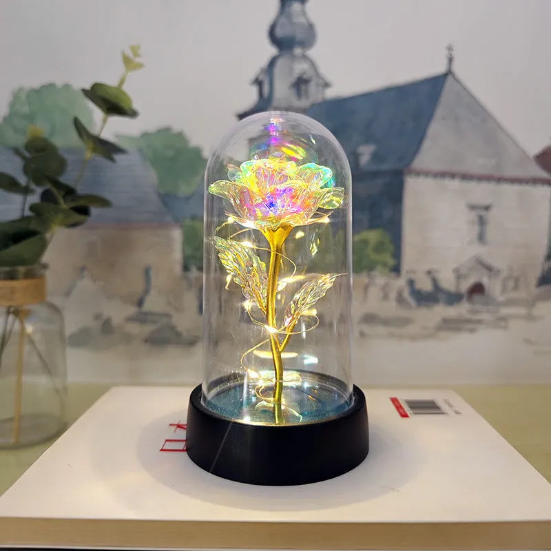 Small glass night lamp with plastic flowers on a black base.