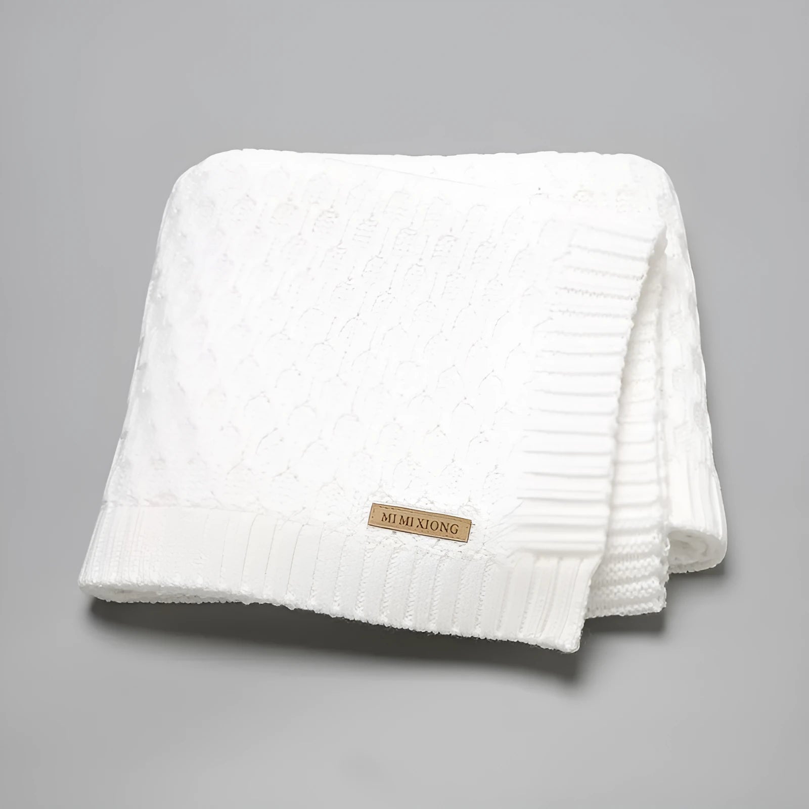Infant hug blanket with three-dimensional lines pattern in a solid colour, measuring 70 by 90 centimetres.