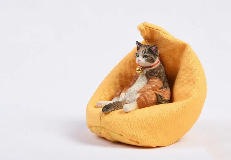 Small resin ornament of a cat sleeping on a sofa for car dashboard or shelf decoration.