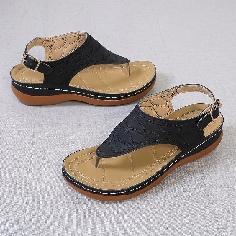 Women's black wedge heel sandals with an adjustable back strap buckle on a white background.