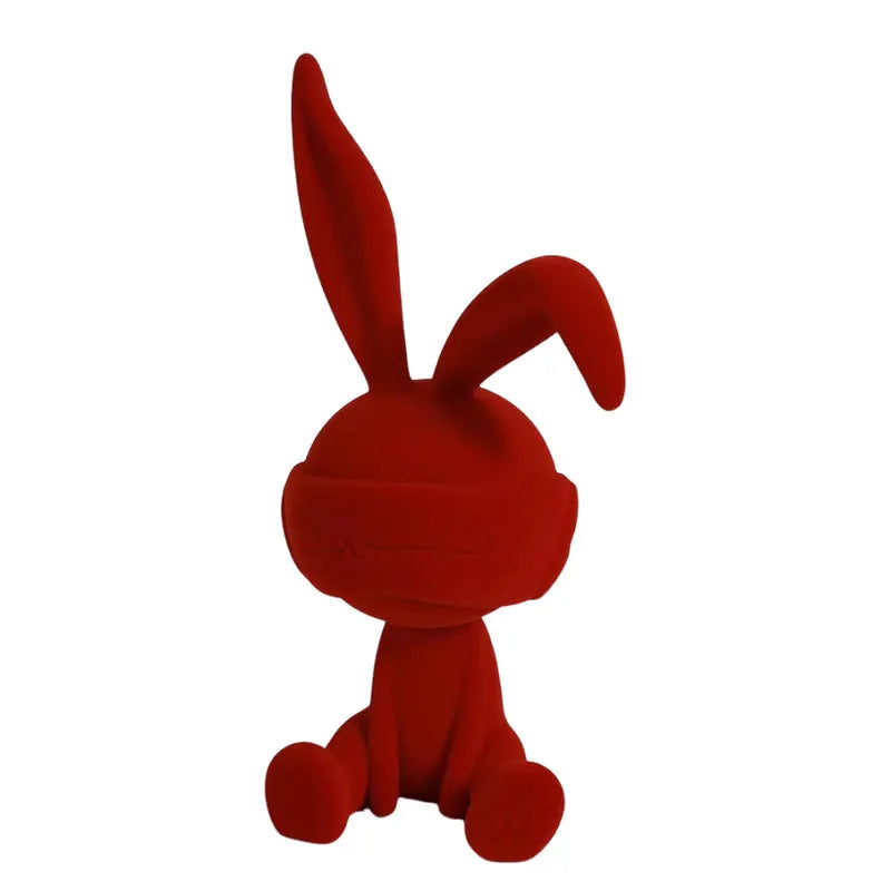 Resin table ornament of a rabbit wearing a suede blindfold with ribbon and tassel detail.