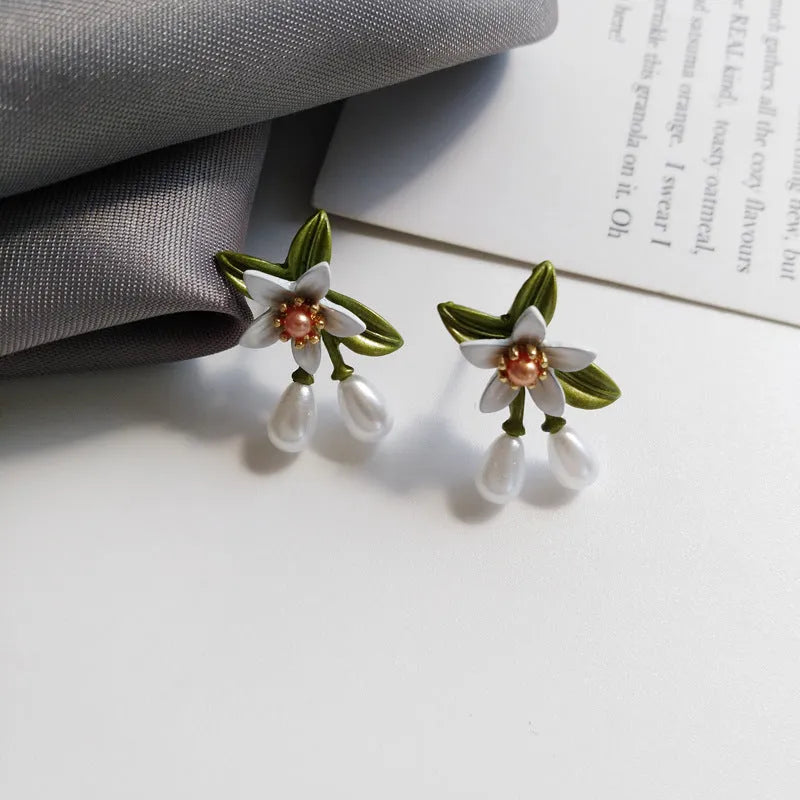 A pair of women's alloy flower earrings shown in two style options: sterling silver needle flowers and a coloured flower clip.