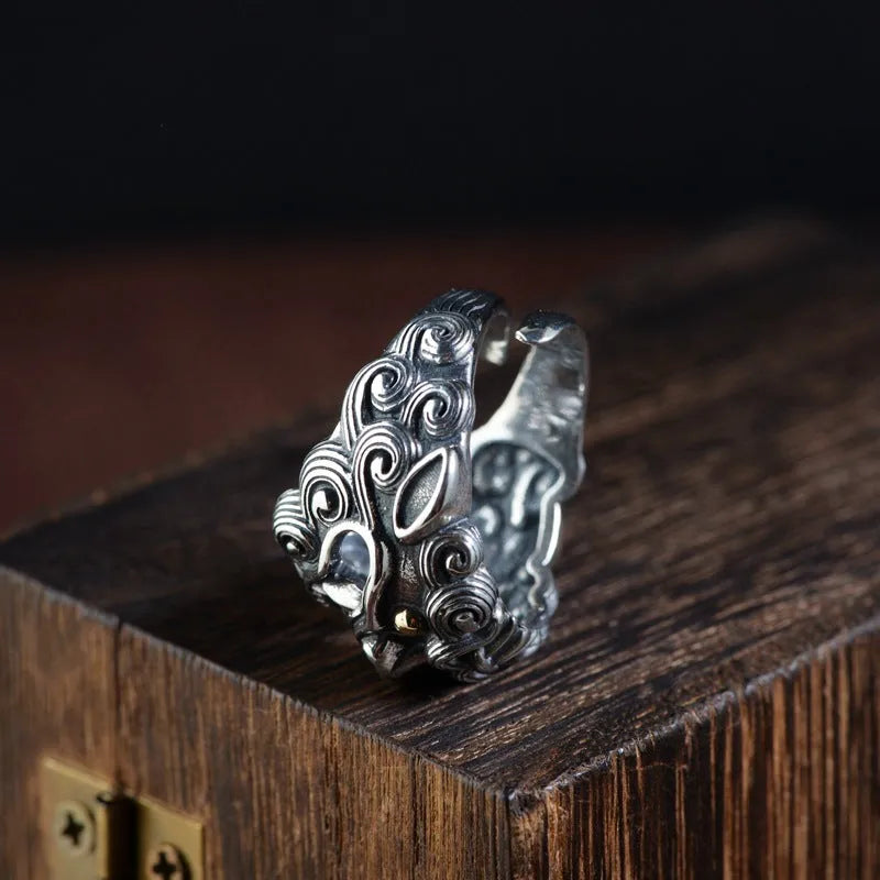 Silver open ring with a detailed domineering Jibeast animal pattern on a model's finger.