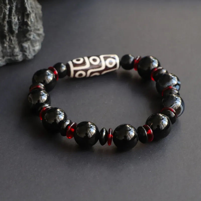 Hand-woven black agate dzi bead bracelet with 11mm geometric beads on a wrist.