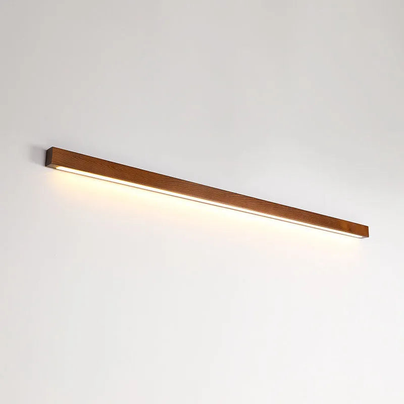 Modern walnut-colour wood log strip wall lamp with integrated LED lighting mounted on a wall.