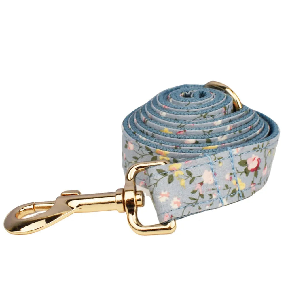 Blue floral patterned dog collar with matching accessories including leash, bow, vest, and poop bag