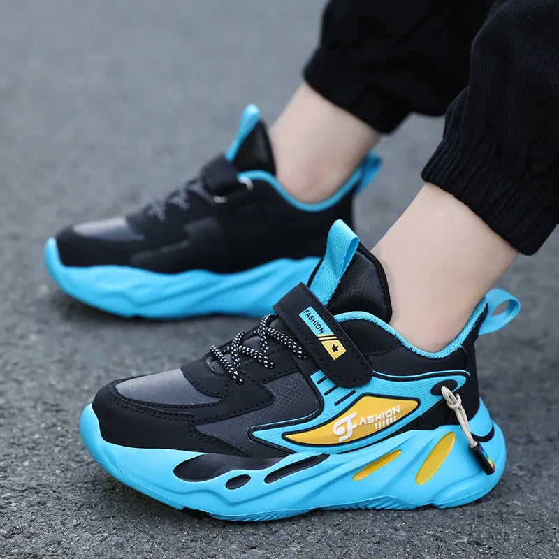 Boys' blue and black platform sports running shoes with Velcro straps on a hard ground surface.