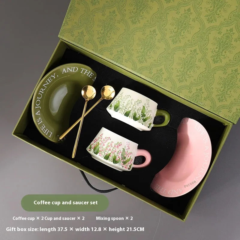 Ceramic coffee cup set with two matching cups, saucers, and stirring spoons featuring hand-painted couple designs