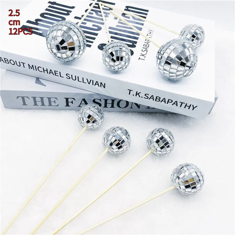 Glass disco ball cake decoration on wooden stick, showing reflective surface.