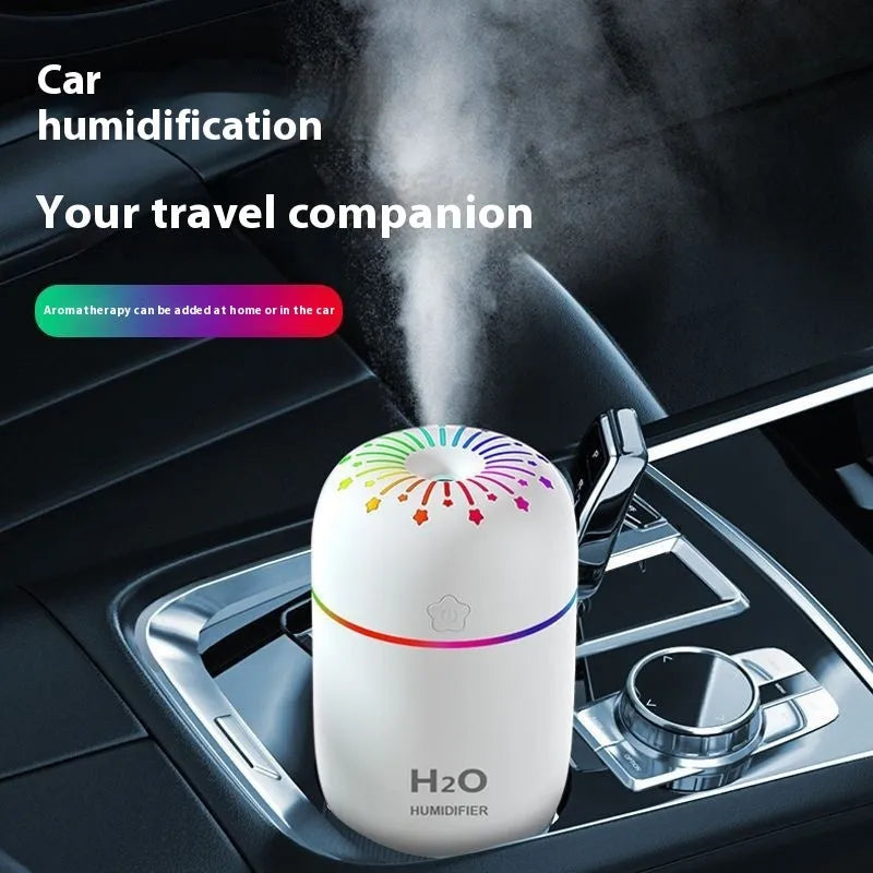 Small white USB-powered mini humidifier with water tank on a desk next to a laptop.