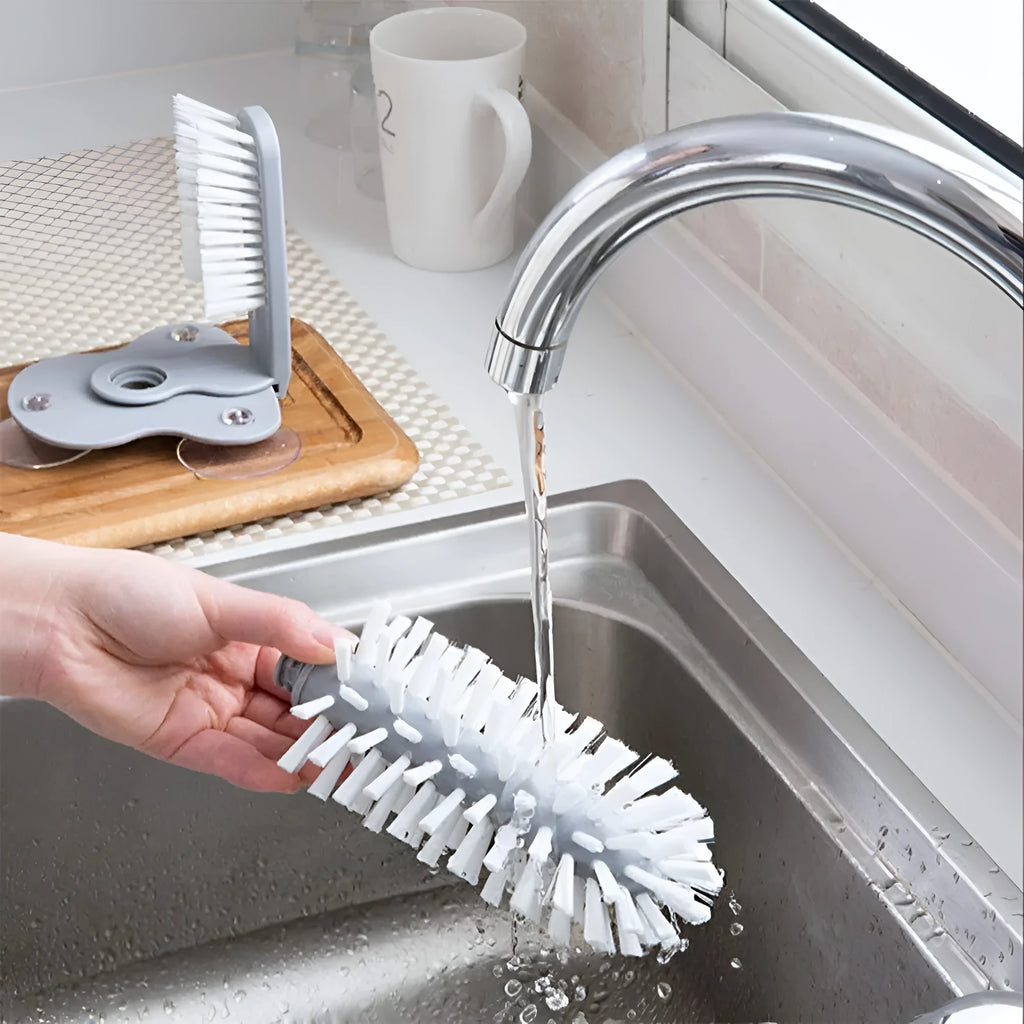 Grey 2 in 1 cup scrubber with double-sided bristles and three suction cups on the base for cleaning glassware.