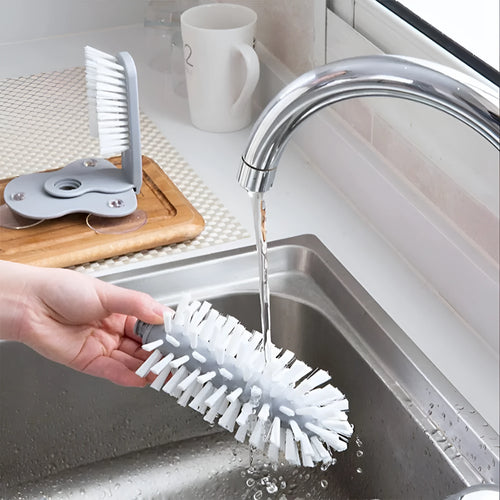 Grey 2 in 1 cup scrubber with double-sided bristles and three suction cups on the base for cleaning glassware.