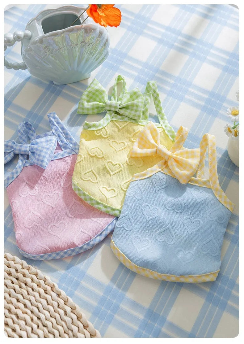 Small dog wearing blue elastic vest with heart pattern and bow suspenders