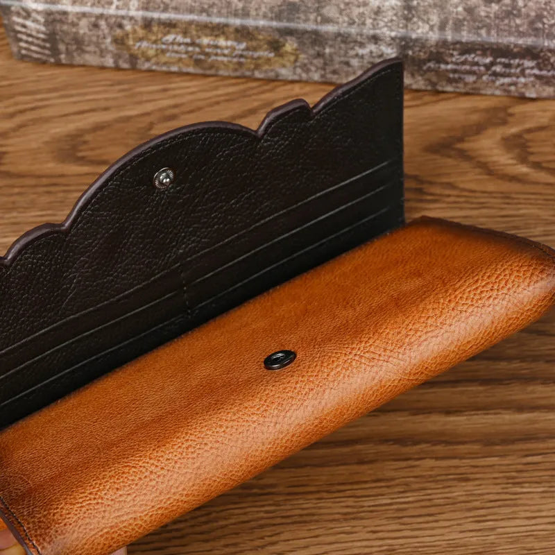 Women's brown tri-fold leather wallet with embossed floral pattern showing interior card slots